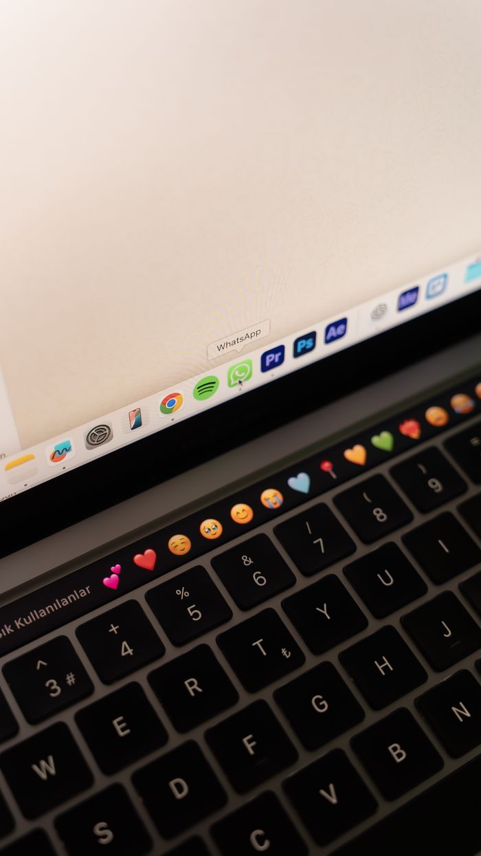 Close-up of a laptop keyboard showing emojis and application icons.